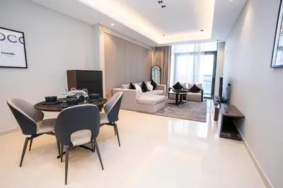 a living room with a table and chairs and a couch at Elegant 2BR Apt Nobles Tower with Pool and Gym in Dubai