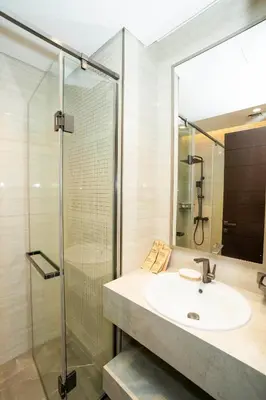 a bathroom with a sink and a glass shower at Elegant 2BR Apt Nobles Tower with Pool and Gym in Dubai