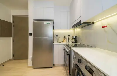 a kitchen with a stainless steel refrigerator and white cabinets at Stylish 1BR Apartment in Binghatti Luna JVC Dubai in Dubai
