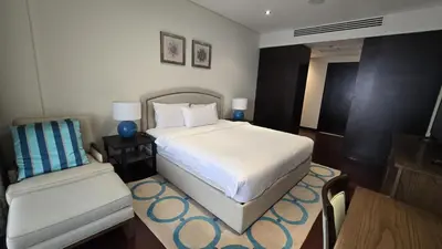 a bedroom with a white bed and a chair at Stunning 1BR at Anantara Sea Views Palm Jumeirah in Dubai