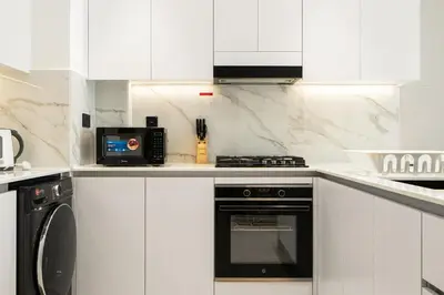 a white kitchen with a stove and a microwave at Luxury 1BR Apt Binghatti Amber Prime Location in Dubai