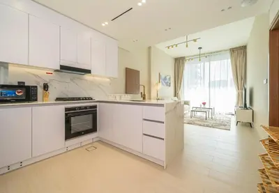 a kitchen with white cabinets and a large window at Stylish Comfort Modern 1BR Apt Prime Location JVC in Dubai