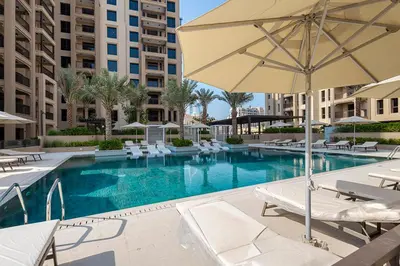 a large swimming pool with chairs and an umbrella at Stylish Studio With Pool View Mins to Dubai Mall in Dubai
