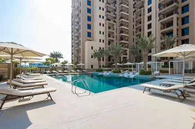 a swimming pool with lounge chairs and umbrellas at Stylish Studio With Pool View Mins to Dubai Mall in Dubai
