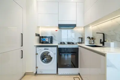 a white kitchen with a washing machine in it at Comfortable 1-Bedroom Getaway Binghatti House in Dubai