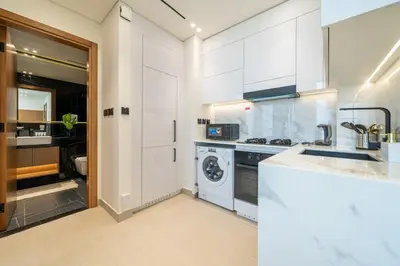 a kitchen with white cabinets and a washing machine at Comfortable 1-Bedroom Getaway Binghatti House in Dubai