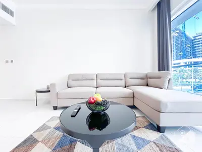 a living room with a couch and a table at Stylish 1-Bedroom Retreat with Balcony Views in Dubai
