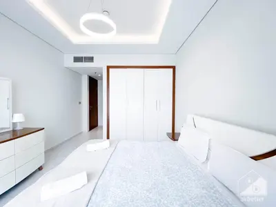 a white bedroom with a bed and a tv at Stylish 1-Bedroom Retreat with Balcony Views in Dubai