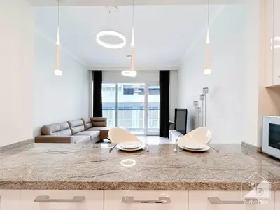 a kitchen and living room with a large counter top at Stylish 1-Bedroom Retreat with Balcony Views in Dubai