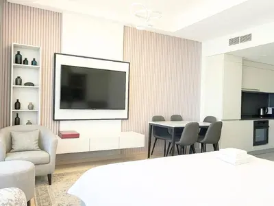 a living room with a tv and a table and chairs at Dream Shoma -Cozy Studio In Business Bay in Dubai