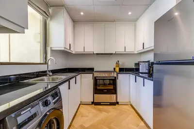 a kitchen with white cabinets and a sink and a dishwasher at Rimal 1 in JBR - 1 Bedroom Apartment - Allsopp & Allsopp in Dubai