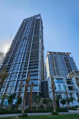 a tall building with palm trees in front of it at Modern 1 BR in Creek Edge Ideal Family Living in Dubai