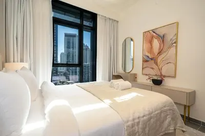 a bedroom with a white bed and a large window at Modern 1 BR in Creek Edge Ideal Family Living in Dubai