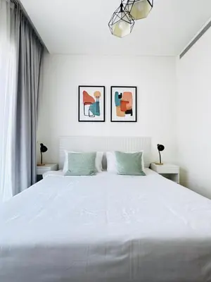 a bedroom with a large white bed with two tables at Cozy 1br in Sobha Creek Vistas Creek Sea View in Dubai