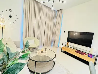 a living room with a tv and a glass table at Cozy 1br in Sobha Creek Vistas Creek Sea View in Dubai