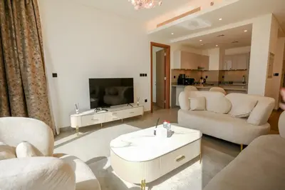 a living room with two white couches and a tv at SOBHA Hartland Grande 1 BHK in Dubai