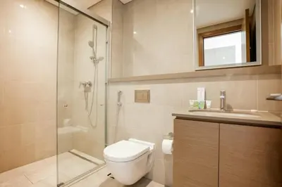 a bathroom with a toilet and a shower and a sink at SOBHA Hartland Grande 1 BHK in Dubai