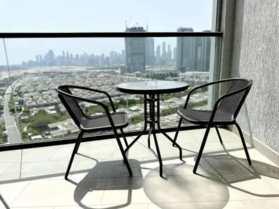 two chairs and a table on a balcony with a view at SOBHA Hartland Grande 1 BHK in Dubai
