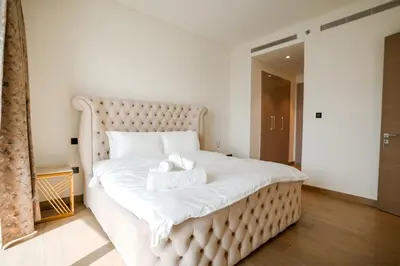 a large white bed with two towels on it at SOBHA Hartland Grande 1 BHK in Dubai