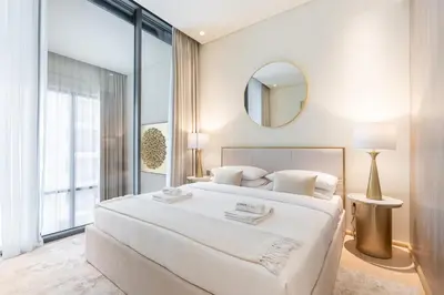 a white bedroom with a large bed and a mirror at Chic Duplex 1BHK by CzechIn Luxe Stay with Pool Gym in Dubai