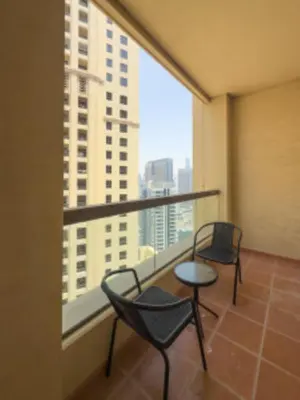 two chairs and a table on a balcony with a large window at Nasma Luxury Stays - Jacuzzi Dreams 1 BR in Jumeirah in Dubai