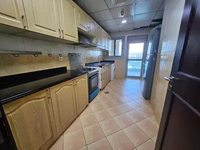 a kitchen with wooden cabinets and a tile floor at Budget Spacious Room Heart of marina in Dubai