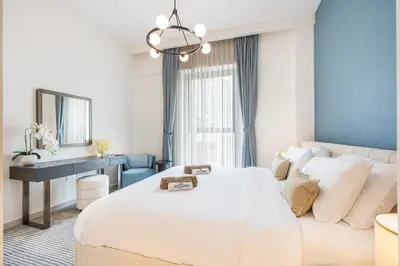 a bedroom with a large white bed and a desk at Lux Creek Home with Burj View steps from the Lagoon in Dubai