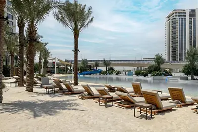 a row of lounge chairs and palm trees on a beach at Lux Creek Home with Burj View steps from the Lagoon in Dubai