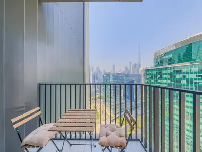 a balcony with a wooden table and chairs on a building at TRPS - Ahad Residences, Business Bay - Full Burj Khalifa View - Modern Furnished Studio in Dubai