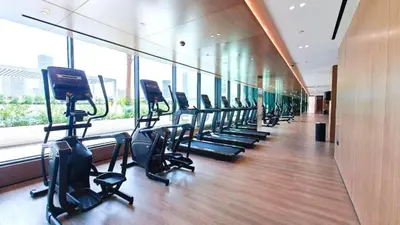 a gym with a row of treadmills in a building at Sky Level 1BR with Lake View and City Glimpse, Close Proximity to Community Park, Binghatti Onyx, Jumeirah Village Circle by Deluxe Holiday Homes in Dubai