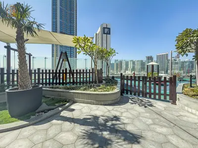 a park with a fence and palm trees in front of a city at Elegant 2 Bedroom Apartment with Pool Views at Business Bay 211DPA-2 in Dubai