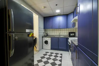 a kitchen with blue cabinets and a black refrigerator at Spacious 1BR with Balcony in JLT Cluster E in Dubai