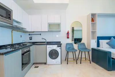 a kitchen with a washing machine and two blue stools at Stylish Studio Bayz Danube Burj Khalifa View Pool in Dubai