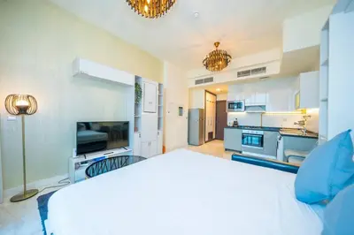 a large bedroom with a white bed and a kitchen at Stylish Studio Bayz Danube Burj Khalifa View Pool in Dubai