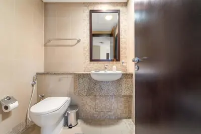 a bathroom with a sink and a toilet and a mirror at Silkhaus Premium 2BDR Stay in Sky Gardens DIFC in Dubai