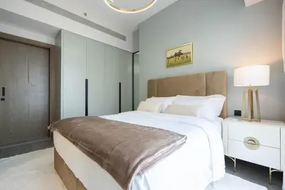 a bedroom with a large white bed and a lamp at KeyRock Golf Gate - Relax and Unwind with Pool and Sauna in Dubai