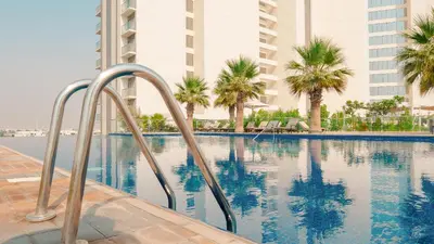 a swimming pool with palm trees and buildings at KeyRock Golf Gate - Stylish Retreat with Pool and Gym in Dubai