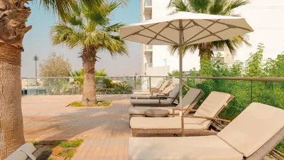 a row of lounge chairs and an umbrella at KeyRock Golf Gate - Stylish Retreat with Pool and Gym in Dubai