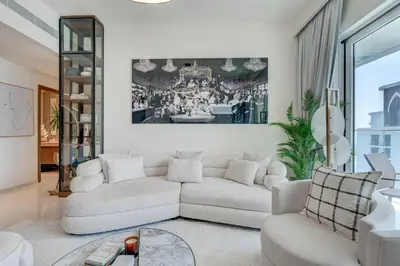 a living room with a white couch and a painting on the wall at Beachfront Bliss 2Bedroom in Grand Bleu in Dubai