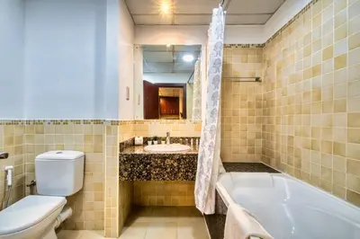 a bathroom with a tub and a toilet and a sink at Modern & Spacious Studio in JBR in Dubai