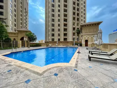 a large swimming pool with two tall buildings at Modern & Spacious Studio in JBR in Dubai