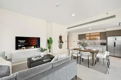 a living room and kitchen with a couch and a table at Golden Stays - Luxury Emaar Beachfront 2BR I Sea & Palm Views in Dubai