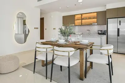 a kitchen with a wooden table and white chairs at Golden Stays - Luxury Emaar Beachfront 2BR I Sea & Palm Views in Dubai