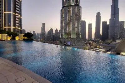 a large swimming pool in a city with tall buildings at Boulevard Point - One Bed with Burj Khalifa View in Dubai