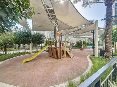 a park with a playground with a slide at Lotus Creek Beach - Opulent One Bed with Pool View in Dubai