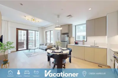a kitchen and a living room with a table at Lotus Creek Beach - Opulent One Bed with Pool View in Dubai