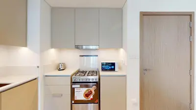 a kitchen with a stove top oven next to a door at Lotus Creek Beach - Opulent One Bed with Pool View in Dubai