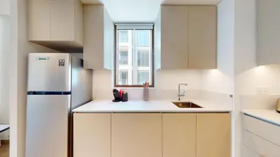 a white kitchen with a sink and a refrigerator at Lotus Creek Beach - Opulent One Bed with Pool View in Dubai