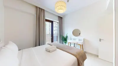 a white bedroom with a bed and a window at Lotus Creek Beach - Opulent One Bed with Pool View in Dubai