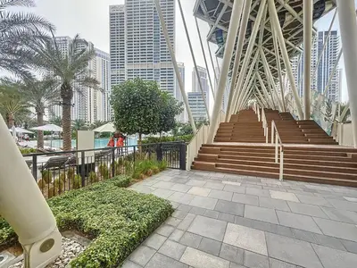 a bridge with stairs in a city with tall buildings at Lotus Creek Beach - Opulent One Bed with Pool View in Dubai